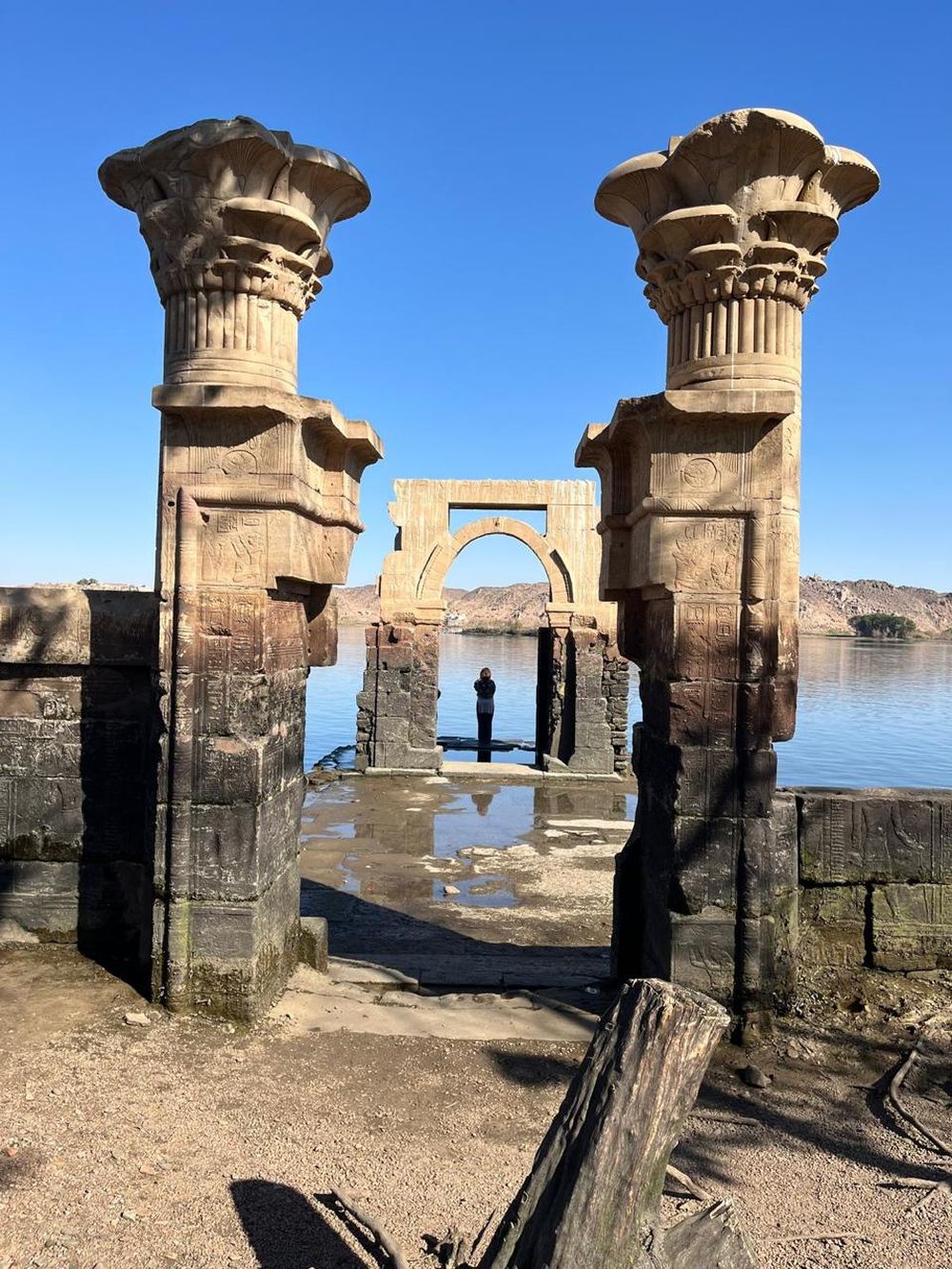 Standing small among the great columns by the water